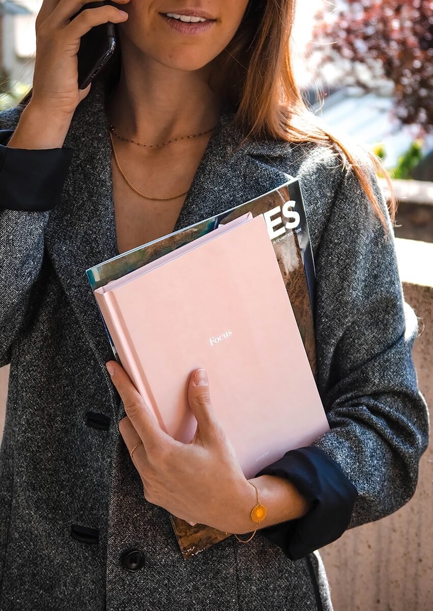 Femme en gilet gris tenant un livre blanc